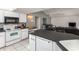 Bright kitchen features white cabinets, black countertop and appliances plus open layout to living area at 128 Torrington St, Port Charlotte, FL 33954