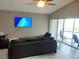 This living room includes tile flooring, a ceiling fan, TV, and sliding glass door access to the pool at 128 Torrington St, Port Charlotte, FL 33954