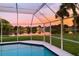Screened-in pool offers stunning sunset views over the tranquil lake at 128 Torrington St, Port Charlotte, FL 33954