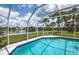 Screened pool area offers stunning lake views with swaying palm trees at 128 Torrington St, Port Charlotte, FL 33954