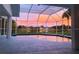 Screened in pool area featuring a tranquil sunset view and a serene lakeside backdrop at 128 Torrington St, Port Charlotte, FL 33954