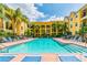 Exterior view of large pool with rows of blue lounge chairs and mature palm trees, a relaxing outdoor space at 1910 E Palm Ave # 10209, Tampa, FL 33605
