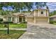 Inviting two-story home boasts a lush lawn, mature trees, and a spacious driveway leading to a three-car garage at 19207 Autumn Woods Ave, Tampa, FL 33647