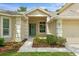 Close-up of the home's entrance featuring a charming green door adorned with a wreath and manicured landscaping at 19207 Autumn Woods Ave, Tampa, FL 33647