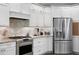 Close-up of a kitchen with stainless appliances, tiled backsplash, granite countertops and white cabinetry at 19207 Autumn Woods Ave, Tampa, FL 33647