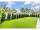Backyard with manicured artificial turf and a white fence at 19400 Roseate Dr, Lutz, FL 33558