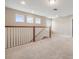 Upstairs hallway features natural light with a wood railing and neutral carpeting at 19400 Roseate Dr, Lutz, FL 33558