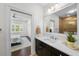 Bathroom featuring black cabinets, white marble countertop, a large mirror, and access to a bedroom at 2303 S Occident St, Tampa, FL 33629