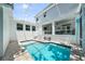 A screened pool is surrounded by travertine pavers and a covered patio with furniture at 2303 S Occident St, Tampa, FL 33629