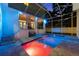 A screened pool with vibrant lighting, surrounded by travertine pavers and a covered patio with furniture at 2303 S Occident St, Tampa, FL 33629