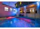 A screened pool with vibrant lighting, surrounded by travertine pavers and a covered patio with furniture at 2303 S Occident St, Tampa, FL 33629