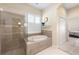 Bright bathroom featuring a soaking tub, separate shower, and neutral tile at 2402 Blue Stone Ct, Valrico, FL 33594