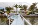 Beautiful yellow waterfront home featuring a private dock with lounge chairs and a boat at 2487 W Bay Isle Se Dr, St Petersburg, FL 33705