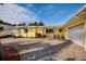 Charming yellow home featuring an expansive brick driveway, a two-car garage, and tropical landscaping at 2487 W Bay Isle Se Dr, St Petersburg, FL 33705