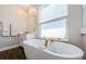 Relaxing bathroom featuring a soaking tub, a window, and a vanity with white cabinets at 2653 Longleaf Pine Pt, New Port Richey, FL 34655