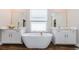 Bright bathroom featuring a soaking tub, white vanities, and a large window with natural light at 2653 Longleaf Pine Pt, New Port Richey, FL 34655