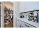 Well-organized walk-in pantry with white shelving next to a kitchen with bright white cabinets and countertops at 2653 Longleaf Pine Pt, New Port Richey, FL 34655