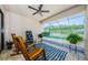Covered patio featuring rocking chairs, ceiling fan, and a view of the sparkling pool with a screened enclosure at 2653 Longleaf Pine Pt, New Port Richey, FL 34655