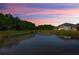 Backyard pond view with lush green surroundings and reflections of the colorful evening sky at 2653 Longleaf Pine Pt, New Port Richey, FL 34655