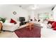 Bright living room with white furniture, red pillows, ceiling fan, television and access to lanai at 29542 Forest Glen Dr, Wesley Chapel, FL 33543