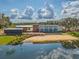 Contemporary waterfront home featuring clean lines, large windows, and stunning views of the adjacent pond at 3303 Monroe Meadows Dr, Odessa, FL 33556
