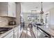Open kitchen with white cabinets, stainless steel appliances, stone countertops, and light hardwood flooring at 3303 Monroe Meadows Dr, Odessa, FL 33556