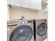 Modern laundry room features front loading washer and dryer with overhead cabinets for convenient storage at 3303 Monroe Meadows Dr, Odessa, FL 33556