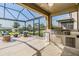 Outdoor kitchen on the screened patio includes built-in grill, sink and seating area at 3303 Monroe Meadows Dr, Odessa, FL 33556