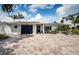 Charming home featuring a paver driveway, manicured landscaping, a blue garage door, and neutral exterior paint at 333 Belleair Ne Dr, St Petersburg, FL 33704
