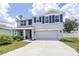 Two-story home featuring gray stucco, dark shutters, an attached two-car garage, and well-maintained landscaping at 36398 Spanish Rose Dr, Dade City, FL 33525