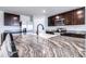 Close-up of the kitchen island with granite countertops, a stainless steel faucet, and dark brown cabinetry at 36398 Spanish Rose Dr, Dade City, FL 33525