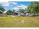 A white home showcases a backyard with patio space, grass, and partial screen enclosure at 36601 Roberts Rd, Dade City, FL 33525
