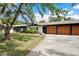 Side view of a home showing a multi-car garage with wooden doors and ample parking space at 36601 Roberts Rd, Dade City, FL 33525