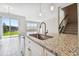 Modern kitchen featuring a granite countertop island, stainless steel appliances, and an adjacent view to the water at 38190 Shale Stone Ct, Zephyrhills, FL 33540