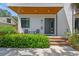 Inviting front porch featuring a wooden deck, black door, modern chairs, and lush greenery, perfect for relaxing at 411 W Frances Ave # 2, Tampa, FL 33602
