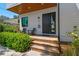 Inviting front porch featuring a wooden deck, black door, modern chairs, and lush greenery, perfect for relaxing at 411 W Frances Ave # 2, Tampa, FL 33602