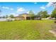 Expansive backyard view showcasing the home, pool enclosure, greenhouse, and additional storage shed at 4180 Jacaranda Cir, Brooksville, FL 34604