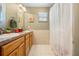 Bathroom with double sinks, wood cabinets, and shower tub combination with a white shower curtain at 4180 Jacaranda Cir, Brooksville, FL 34604