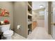 Well-lit bathroom featuring a toilet, shelving, and light wood cabinetry at 4180 Jacaranda Cir, Brooksville, FL 34604