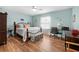 Comfortable bedroom with wood floors, ceiling fan, desk, large bed, and bright accents at 4180 Jacaranda Cir, Brooksville, FL 34604
