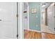 Hallway view featuring wood floors with an entryway to a full bathroom and a doorway with decorations at 4180 Jacaranda Cir, Brooksville, FL 34604