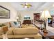 Living room with a ceiling fan, tan sofas, an ornate coffee table, and hardwood floors at 4180 Jacaranda Cir, Brooksville, FL 34604