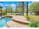 Inviting pool area featuring a stone-accented design, screened enclosure, lounge chair and landscaped surroundings at 4180 Jacaranda Cir, Brooksville, FL 34604