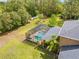 Aerial view of a screened-in pool area in backyard with ample grass surrounding it and tall trees at 4180 Jacaranda Cir, Brooksville, FL 34604