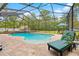 Inviting backyard pool area, enclosed with screening, and complemented by comfortable lounge chairs and lush greenery at 4180 Jacaranda Cir, Brooksville, FL 34604