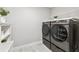 Well-lit laundry room with modern washer and dryer set, shelving, and stylish tile flooring at 4275 Burdick Loop, Odessa, FL 33556