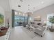 Bright living room with a large chandelier, neutral furniture, and sliding glass doors to an outdoor patio at 4300 Barletta Ct, Wesley Chapel, FL 33543