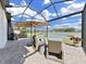 Relaxing screened patio with comfortable wicker chairs, umbrella, and picturesque lake views at 4300 Barletta Ct, Wesley Chapel, FL 33543