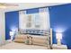 Cozy bedroom featuring white wood bedframe and blue accent wall with beach themed decor at 445 Hamden Dr # 502, Clearwater Beach, FL 33767