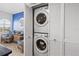 Bright laundry closet featuring a stacked washer and dryer with classic louvered doors at 445 Hamden Dr # 502, Clearwater Beach, FL 33767